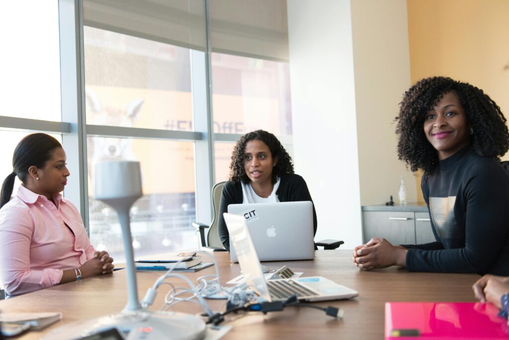 Three professional women engaged in a lively discussion in a modern office setting.